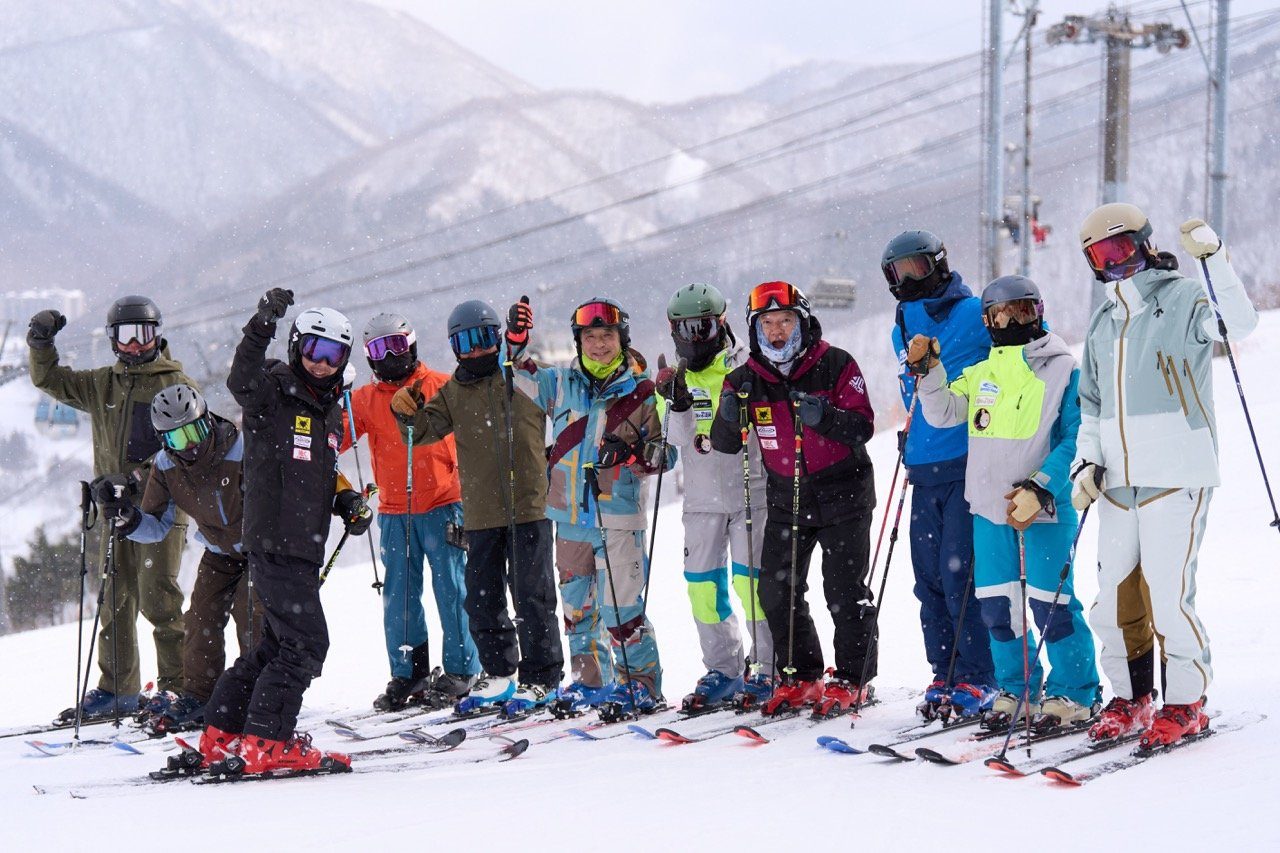 A group raising their hands with the coach in the snow