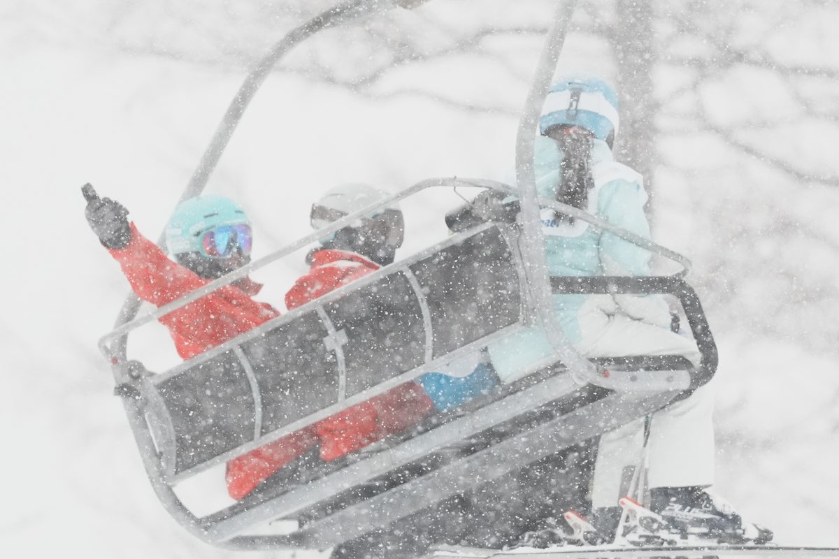 Coach and kids riding the chairlift in the snow